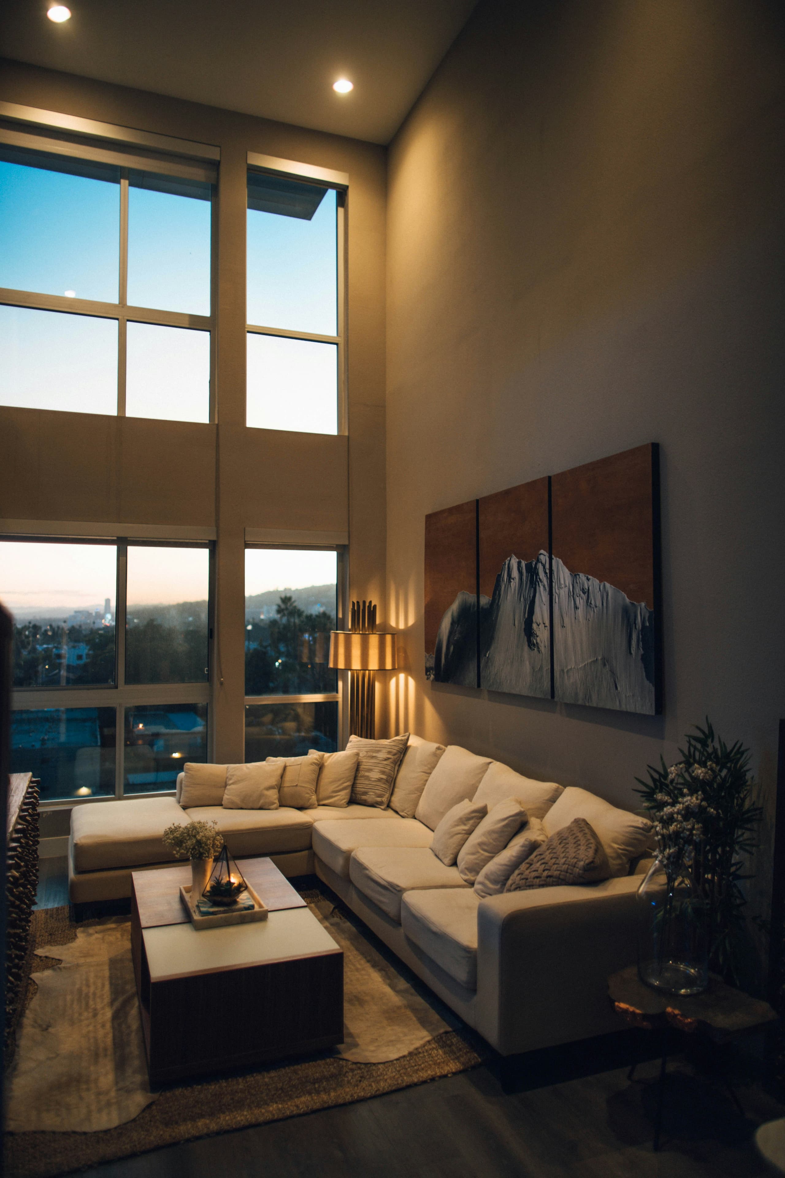 Warm, comfortable open-plan living room at dusk with floor-to-ceiling windows